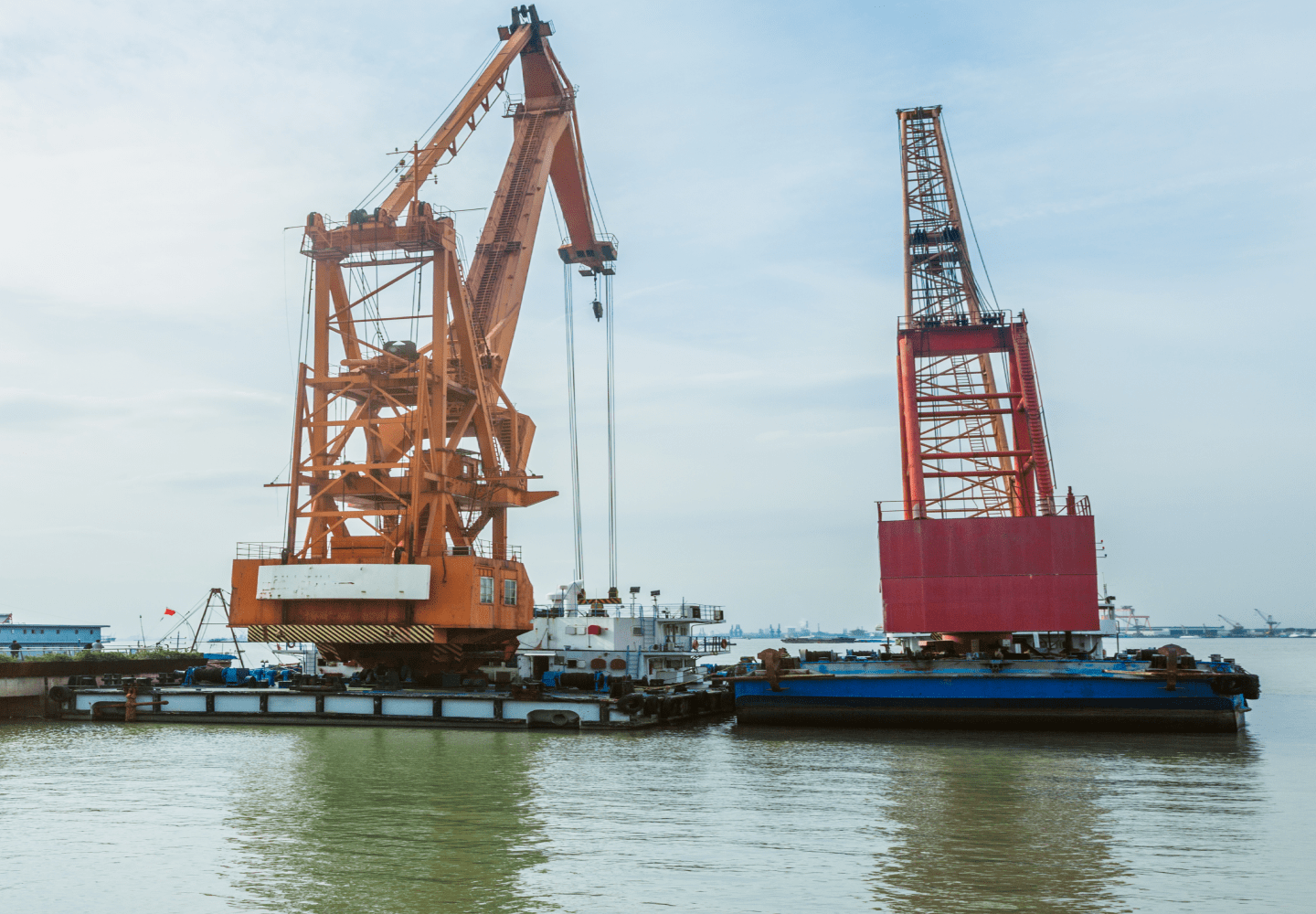 Port crane lifting cargo at harbor with ship in background