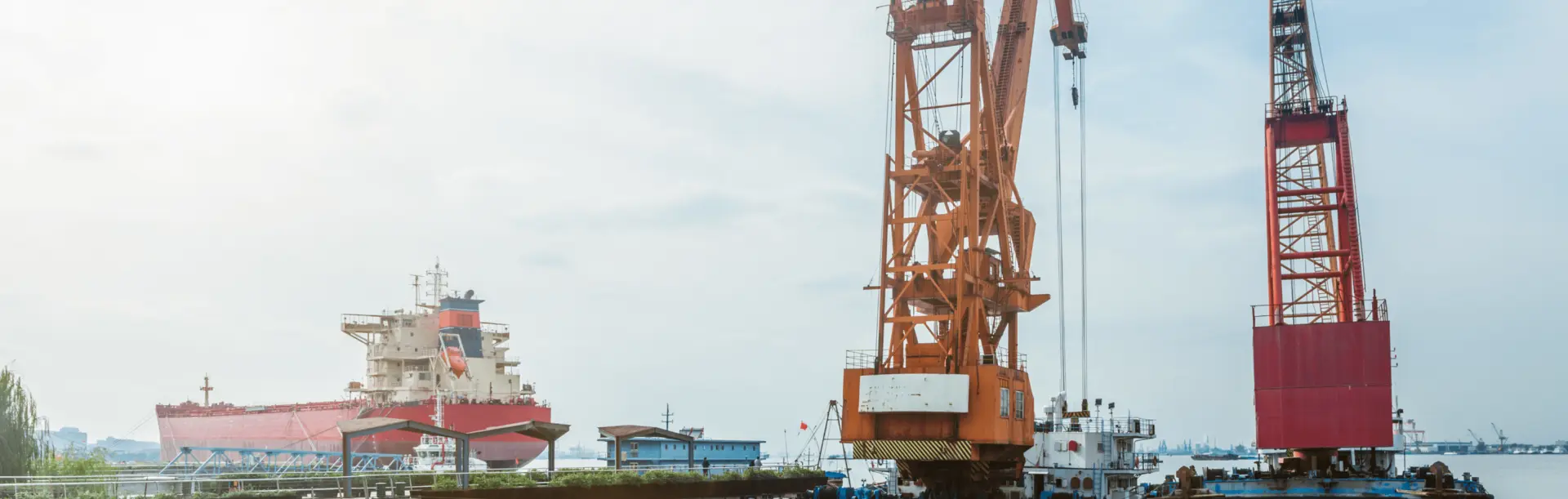 Port crane lifting cargo at harbor with ship in background