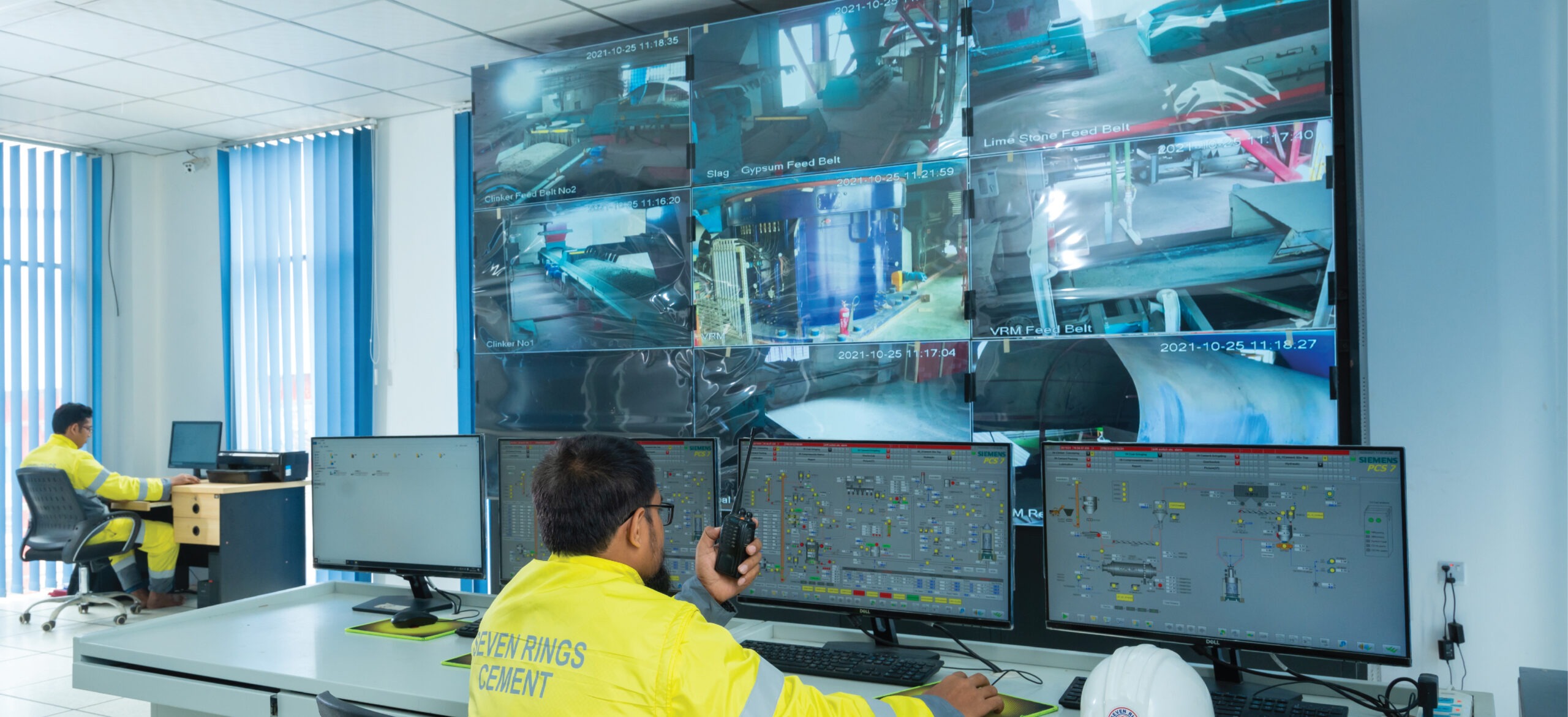 Control room staff monitoring cement production with multiple screens at Seven Rings Cement.
