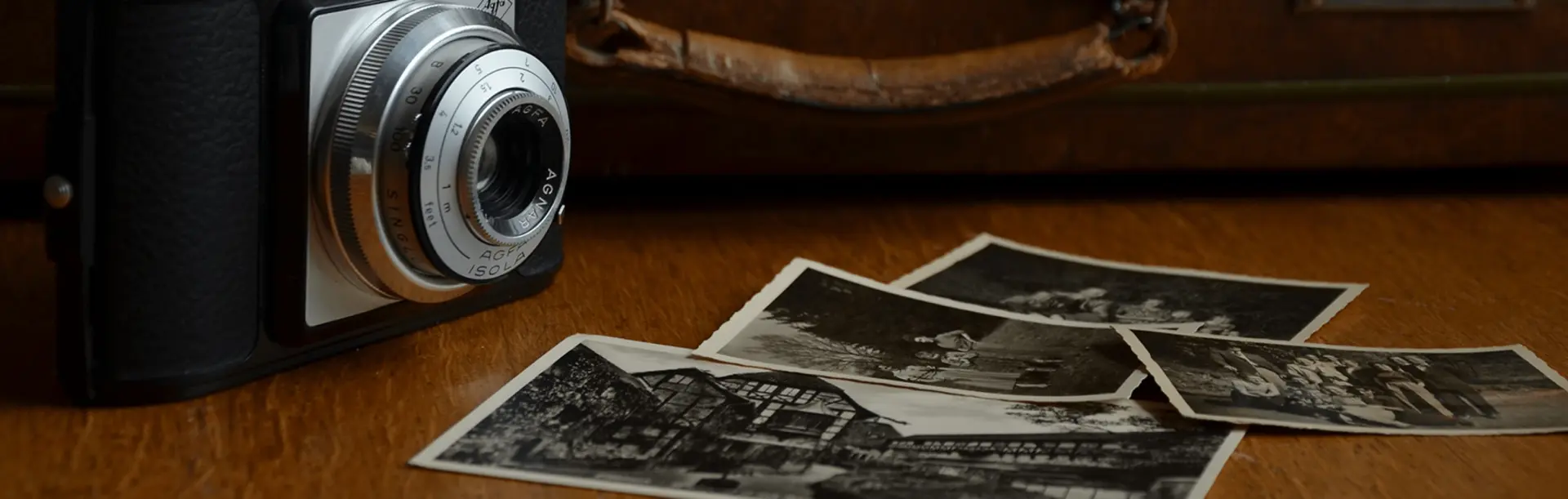 Vintage camera with black and white photos on wooden surface